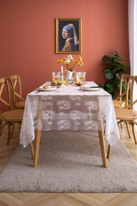 Detailed close-up of intricate white floral lace patterns on a sheer vintage tablecloth