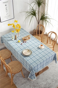 Detailed overhead view of a blue plaid tablecloth with decorative tassels on a wooden table