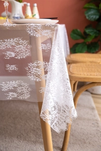 Close-up of elegant white lace tablecloth featuring rose patterns and eyelash fringe edges