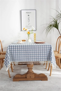 Detail of blue and white plaid tablecloth featuring elegant white tassel edges on wooden table