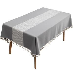Gray rectangular tablecloth with white chevron pattern and tassel edges on wooden table