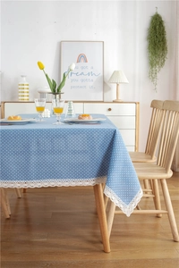 Close-up of blue polka dot table cloth with white hollow lace edges on a wooden table