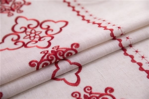 Close-up of beige linen tablecloth featuring traditional red cloud embroidery details