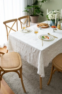 Detailed close-up of white cotton tablecloth featuring textured weave and decorative pom-poms