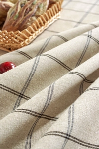 Macro detail of beige linen tablecloth featuring black grid pattern and textured fabric