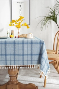 Detail of blue plaid linen tablecloth featuring white cotton tassel fringe and woven texture