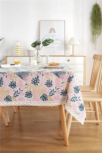 Detail of tropical leaf pattern tablecloth featuring delicate white lace trim and floral texture