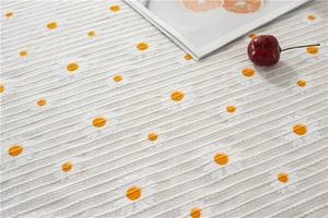 Close-up of white cotton tablecloth with yellow daisy pattern and striped texture