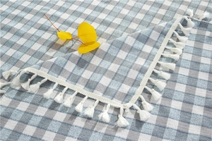 Close-up of geometric plaid tablecloth with fringe edges and silver thread details