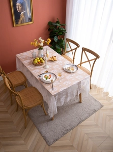 Detail of white lace tablecloth featuring delicate floral patterns and wavy hollowed edges