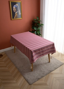 Detail of bohemian style table runner with pink floral stripes and white cotton tassels