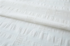 Detailed close-up of white cotton fabric with romantic textured jacquard square patterns