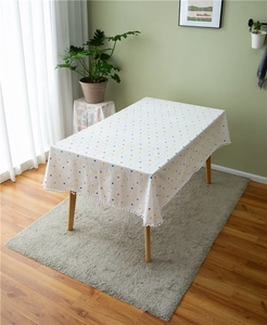 Detail of white cotton tablecloth with colorful dots and elegant white pom-pom fringe