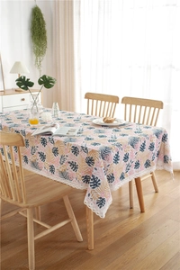 Detailed close-up of tropical palm leaf print tablecloth with elegant white lace border