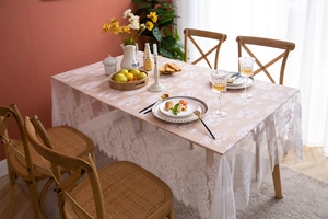 Detailed close-up of white lace tablecloth with floral hollow patterns and wavy borders