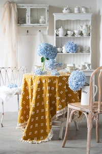 Detail of vintage yellow jacquard tablecloth with 3D tufted squares and short white fringes