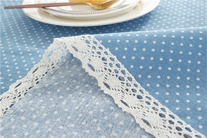 Detailed view of sky blue polka dot tablecloth with elegant white lace border and texture