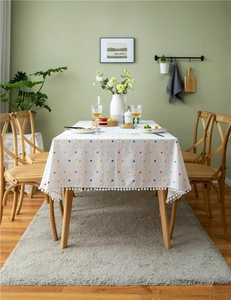 Detail of white cotton tablecloth with colorful polka dots and pom-pom fringe edges