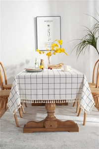 Macro view of checkered tablecloth with decorative white tassels on wooden table