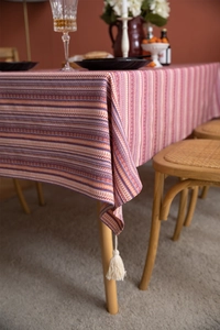Detail of bohemian striped woven tablecloth featuring white cotton decorative tassels