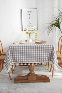 Close-up of grey and white plaid tablecloth featuring decorative white ball tassels