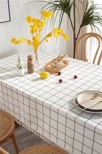 Close-up of minimalist black checkered tablecloth with delicate white tassel fringe edges