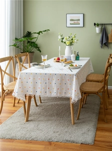 Close-up of white jacquard tablecloth with colorful polka dots and pom-pom edge trim