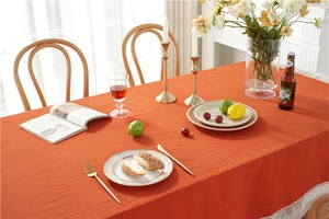 Close-up of orange washed cotton tablecloth with white meteor lace edges and texture