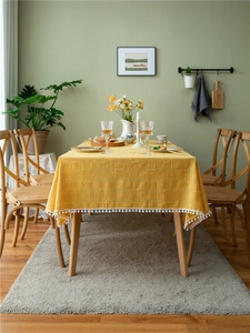 Detailed texture of yellow cotton tablecloth with white pom pom lace and square pattern