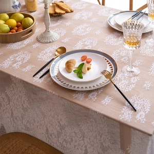 Close-up of vintage white floral lace tablecloth with elegant scalloped edges on a dining table