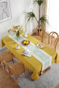 Close-up of ginger yellow cotton tablecloth with ruffled edges and wave pattern runner