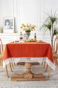 Detailed close-up of burnt orange cotton tablecloth featuring delicate white lace edges