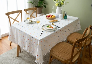 Detail of white cotton tablecloth with colorful dots and white pom-pom tassel edge