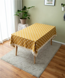 Detail of yellow rectangular tablecloth featuring white jacquard weave and cotton tassels