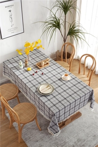 Detail of grey geometric plaid tablecloth with decorative white handmade tassels