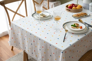 Close-up of colorful polka dot pattern and white pom-pom trim on rectangle cotton tablecloth