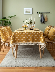 Detail of yellow jacquard tablecloth with white floral embroidery and tassel fringe edges