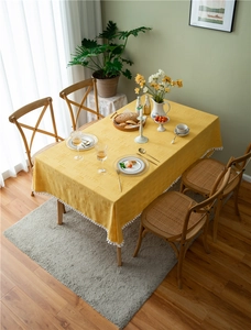 Close-up of yellow embossed tablecloth with white pom-pom fringe in a cozy home setting