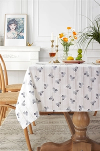 Detail of white cotton tablecloth featuring black floral embroidery and textured stripes