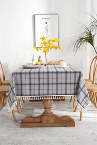 Detail of grey and white checkered tablecloth with decorative white fringe trim edges