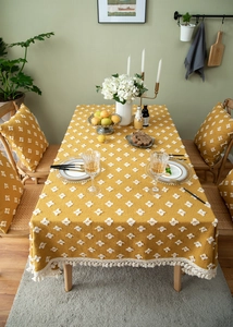 Macro view of mustard yellow tablecloth with white tufted floral patterns and fringe