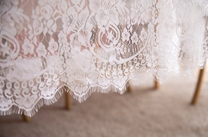Close-up of white floral lace fabric with delicate eyelash trim for wedding table decor
