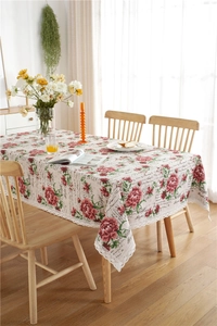 Detail of floral tablecloth featuring red roses and vintage lace trim on wood table