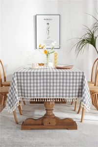 Detailed view of gray and white checkered tablecloth with decorative white tassel edges