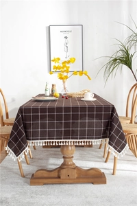 Macro detail of dark brown checkered tablecloth fabric with elegant white tassel fringe