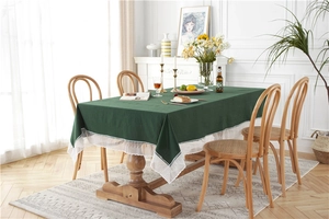 Detailed close-up of dark green cotton tablecloth featuring elegant white lace edges