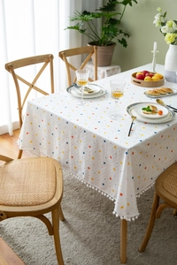 Detail of colorful polka dot cotton tablecloth with white pom-pom fringe edges