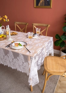 Detailed view of white floral lace tablecloth featuring delicate eyelash trim and rose patterns