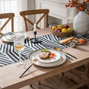 Modern jacquard chenille table runner with black and white geometric V-stripes and tassels