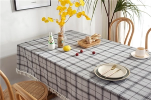 Close-up of gray checkered tablecloth fabric with white cotton fringe tassel details